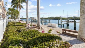 A marina with boats docked, surrounded by palm trees and a white fence. - Waterfront 1/1, sleeps 6, walk to beach! #B111 (Indian Shores)