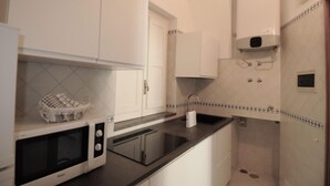 A compact kitchen with white cabinets, a microwave, and a sink. - La Piazzetta by Amalfidreams (MINORI)