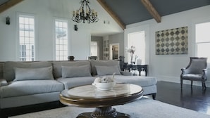 A spacious living room with a light grey sofa, a round coffee table, and a dark wooden chair. - Beautiful Luxury Home near Smyrna Village & Braves Stadium (Smyrna)