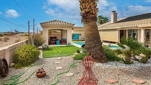 Il s'agit d'une propriété résidentielle dotée d'une terrasse, d'un espace salon extérieur, d'une piscine et d'une pelouse bien entretenue.
