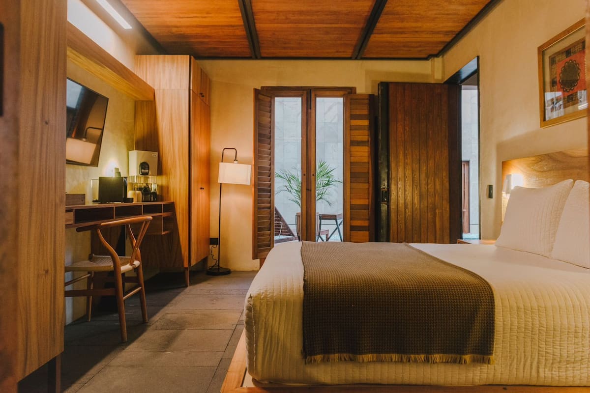 Un dormitorio con cama, escritorio, silla y vista a un balcón.