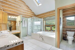 Ein modernes Badezimmer mit einer großen Badewanne, einer separaten Duschkabine und einem Waschtisch.