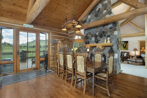 Un comedor de madera con chimenea de piedra, vigas de madera y vistas al exterior.