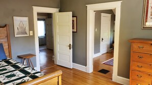A bedroom with a bed, a dresser, and two open doors leading to other rooms. - Yorktown - Historic Yorktown - 3 Bedrooms & 1 Bath. (Yorktown)