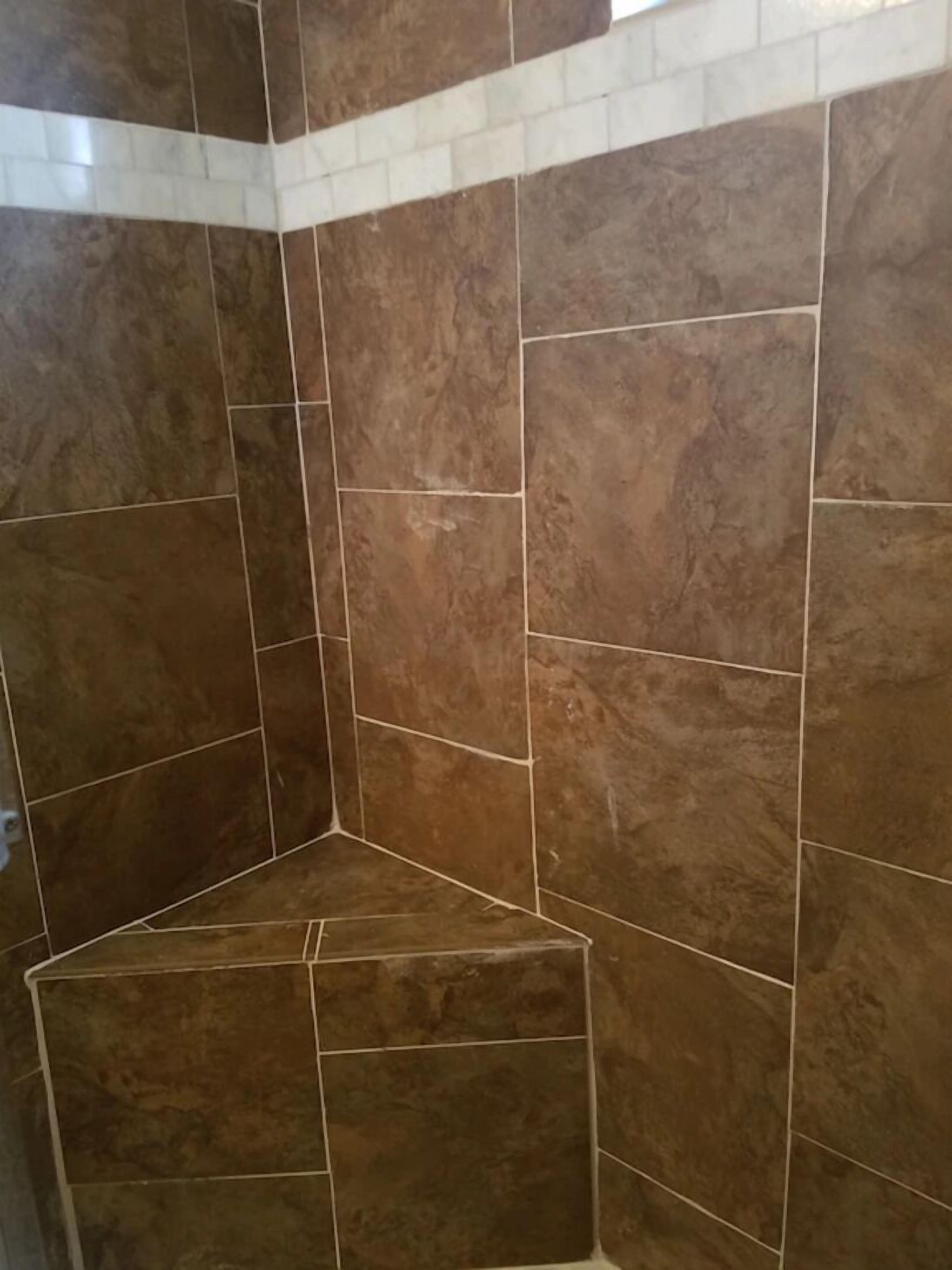 Een hoek van een kamer met bruine betegelde wanden en een witte plint.