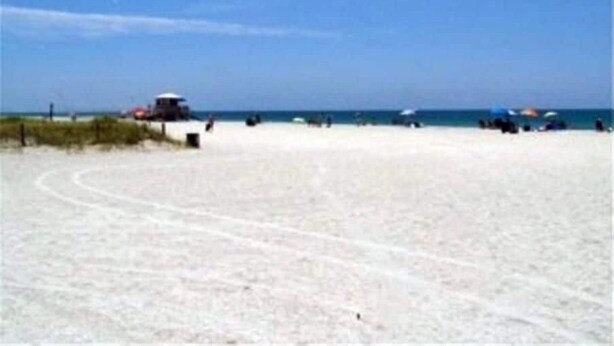 A beach with a sandy shore, a few umbrellas, and a lifeguard tower.
