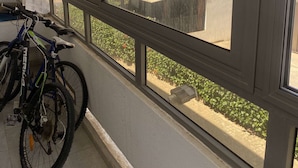 A view from a window with a bicycle leaning against the wall, overlooking a building with a balcony and a flag. - Apartment Marbella beach 24/24 security (El Mansouria)