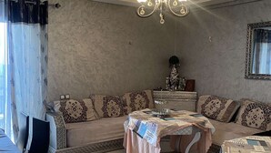 A living room with a sofa, a dining table, and a chandelier. - Apartment Marbella beach 24/24 security (El Mansouria)