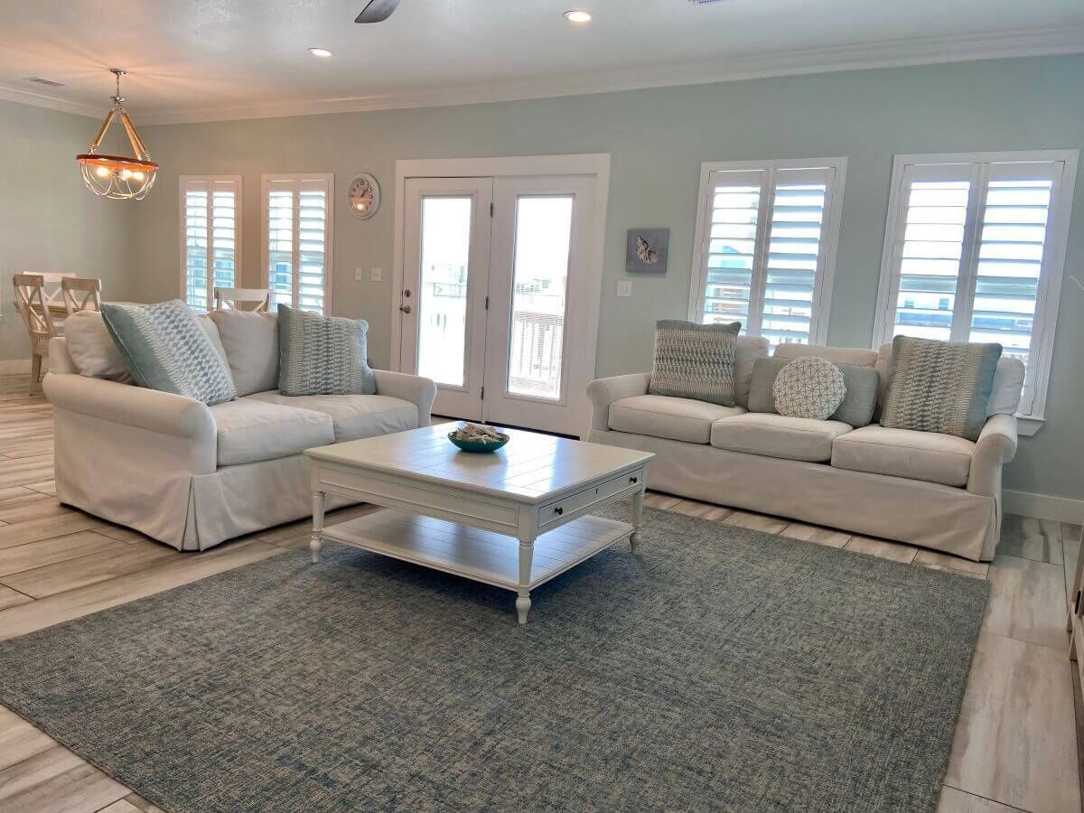 A living room with two white sofas, a coffee table, and a chandelier.
