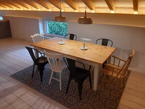 Un coin repas avec une table et des chaises en bois, un tapis à motifs et une fenêtre donnant sur un paysage verdoyant.