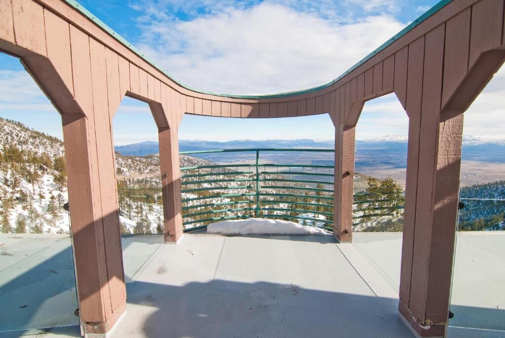 Una plataforma de madera con techo curvo, que ofrece una vista panorámica de un paisaje montañoso.