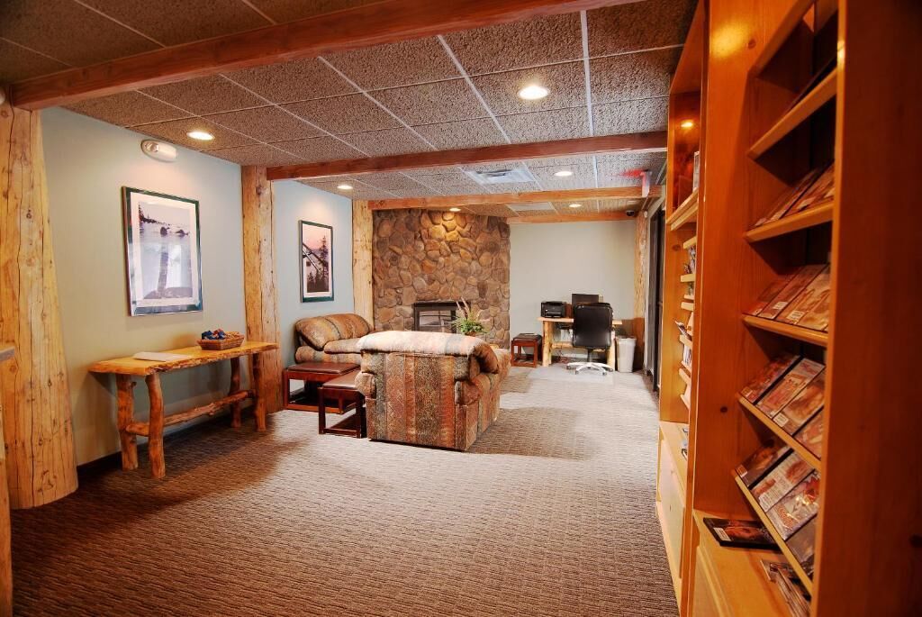 Uma sala de estar aconchegante com lareira de pedra, móveis de madeira e uma estante de livros.