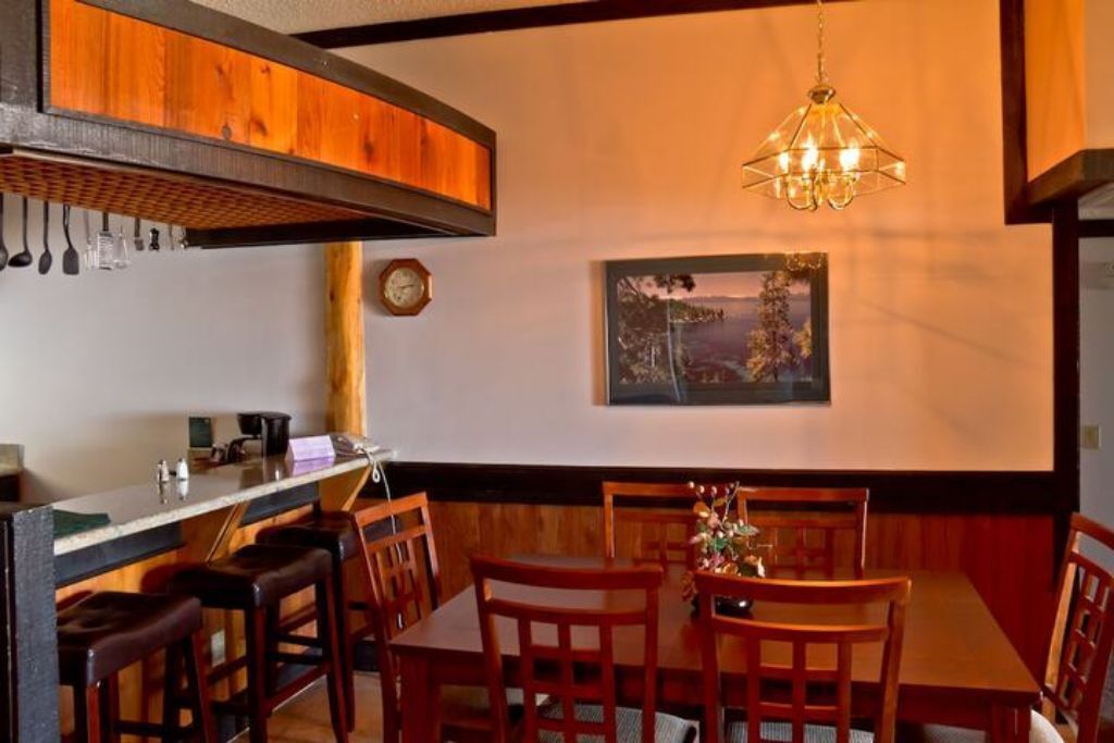 Ein Essbereich mit Holztisch und -stühlen, einer Kristallleuchtre, einer Uhr und einem gerahmten Bild an der Wand.