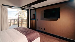 Une chambre d’hôtel avec un lit, un téléviseur fixé au mur et un balcon avec vue.