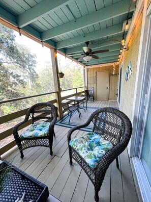 A covered porch with wicker furniture and a ceiling fan.