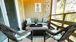 A covered porch with wicker furniture, a ceiling fan, and decorative wall art. - Cozy and Secluded 2BR / 2BA fully equipped condo just a short walk to the beach  (Fernandina Beach)