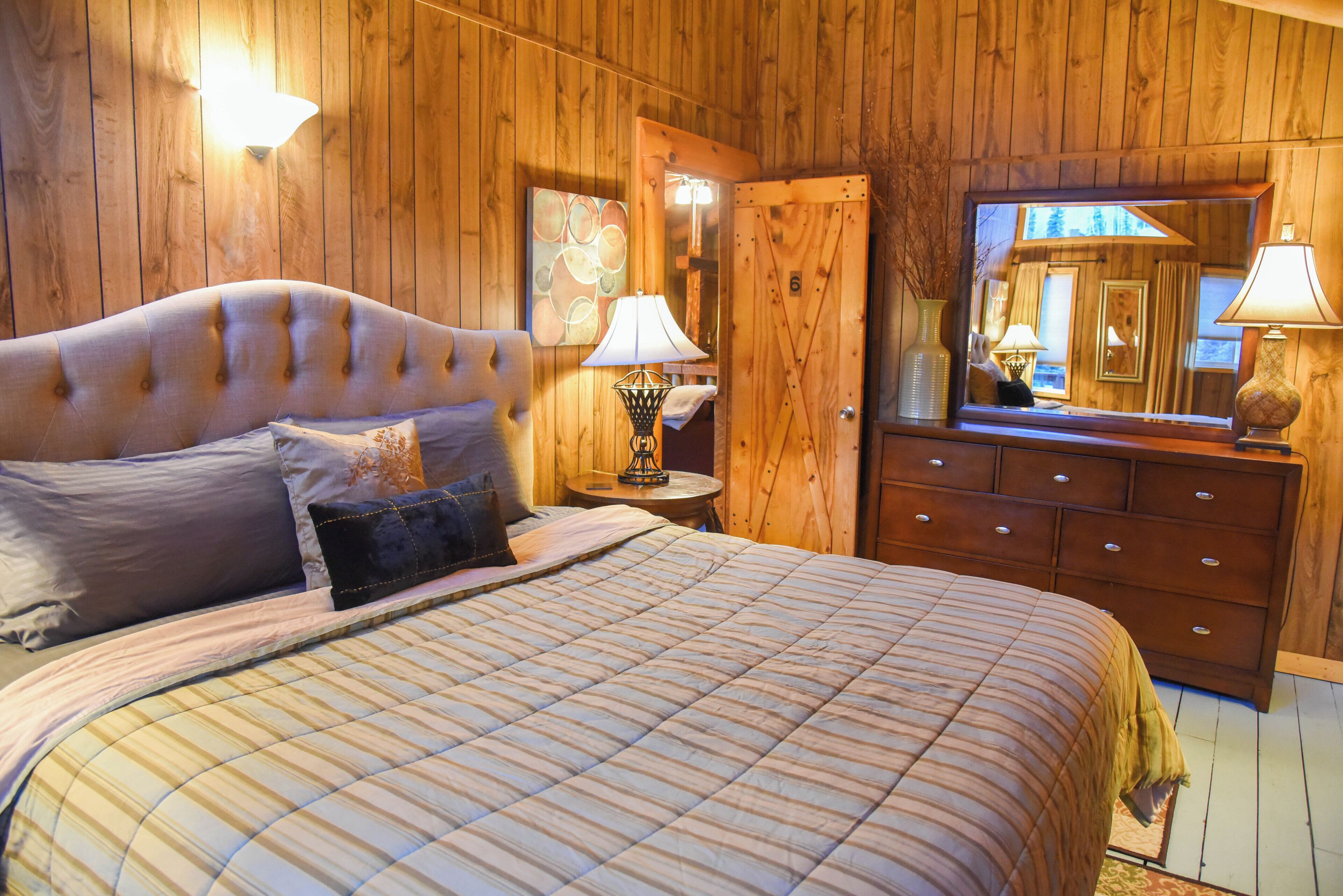 Une chambre à coucher aux murs lambrissés, avec un grand lit, une commode et un miroir.
