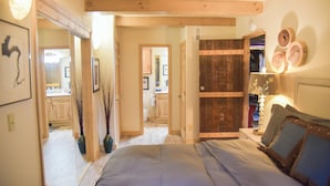 Une chambre à coucher avec un lit, des poutres en bois, une armoire et un miroir qui reflète la pièce.