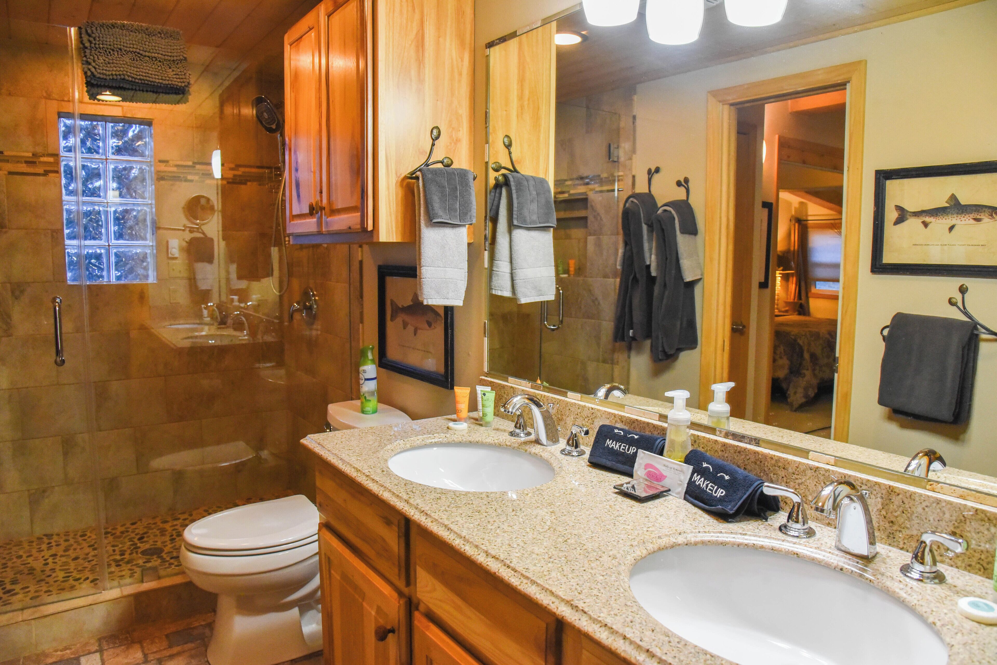 A bathroom with two sinks, a shower, and a large mirror.