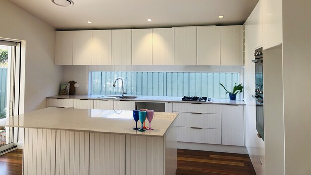 Una cocina moderna con armarios blancos, una isla central y un ventanal con vidrio esmerilado.
