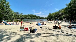 A beach with tents, chairs, and people relaxing. - Spacious Cabin Right Next to Cacapon State Park (Berkeley Springs)