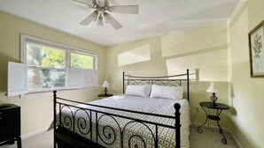 A bedroom with a bed, a ceiling fan, a window, and two bedside tables. - Spacious Cabin Right Next to Cacapon State Park (Berkeley Springs)