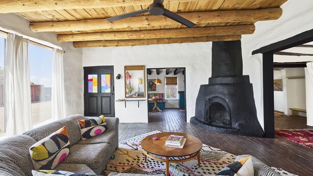A cozy living room with a wooden ceiling, a fireplace, and a sofa with patterned cushions. - Spacious, Stylish “Niji Suite” @ La Dea (Santa Fe)