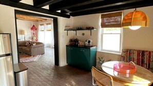 A compact kitchen with a dining area, a kitchenette, and a view of a living room. - Spacious, Stylish “Niji Suite” @ La Dea (Santa Fe)