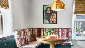 A cozy corner with a wooden table, a colorful patterned bench, and a painting on the wall. - Spacious, Stylish “Niji Suite” @ La Dea (Santa Fe)