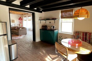 Cozy living space with a kitchenette, dining area, and seating area, featuring a sofa and patterned rug.