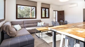 A modern living room with a sofa, ottoman, and a dining table.