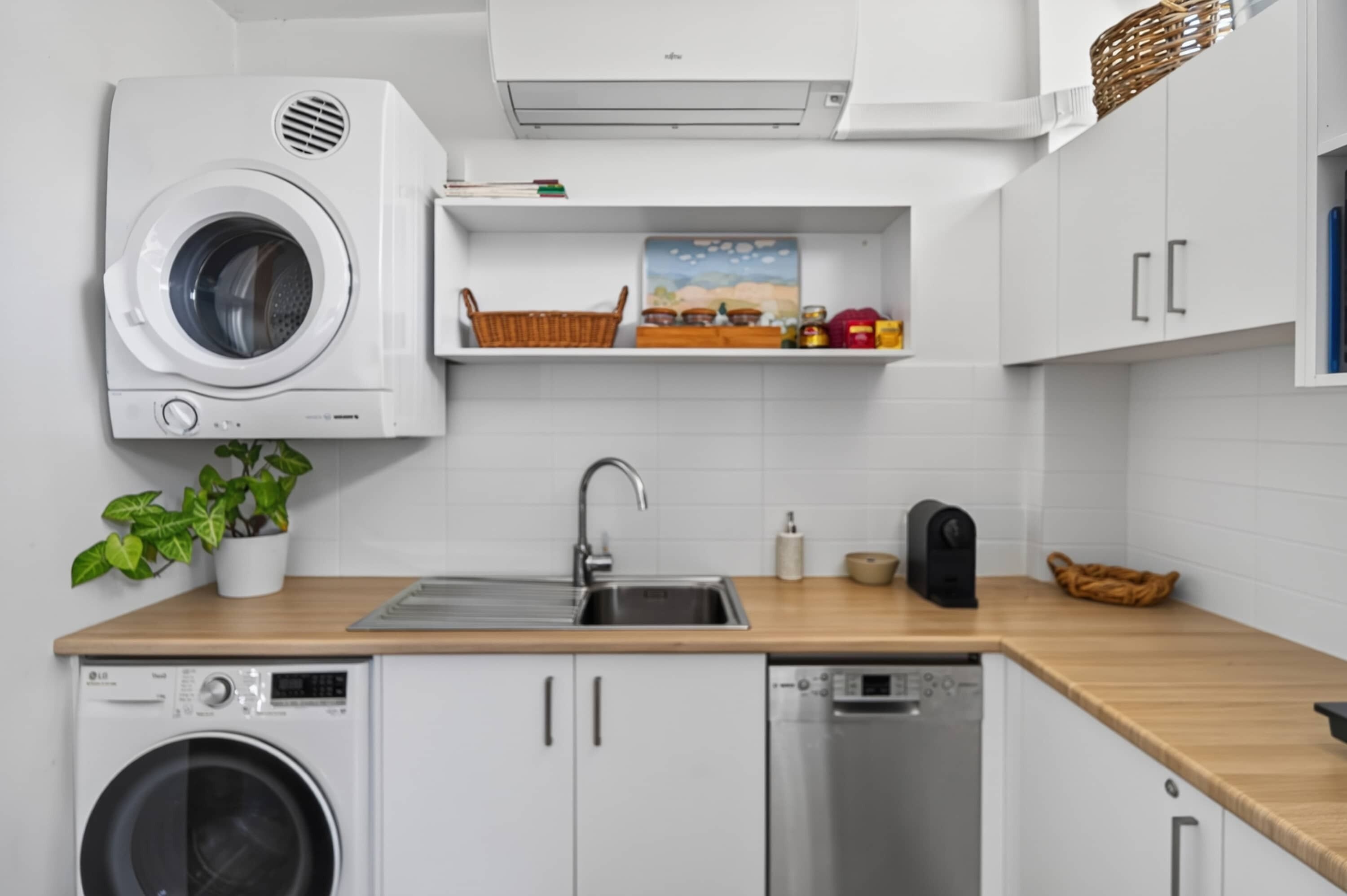 A kitchen with a washing machine, a sink, a microwave, and a dishwasher.