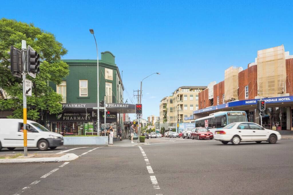 A street corner with a pharmacy, a hotel, and a bus.