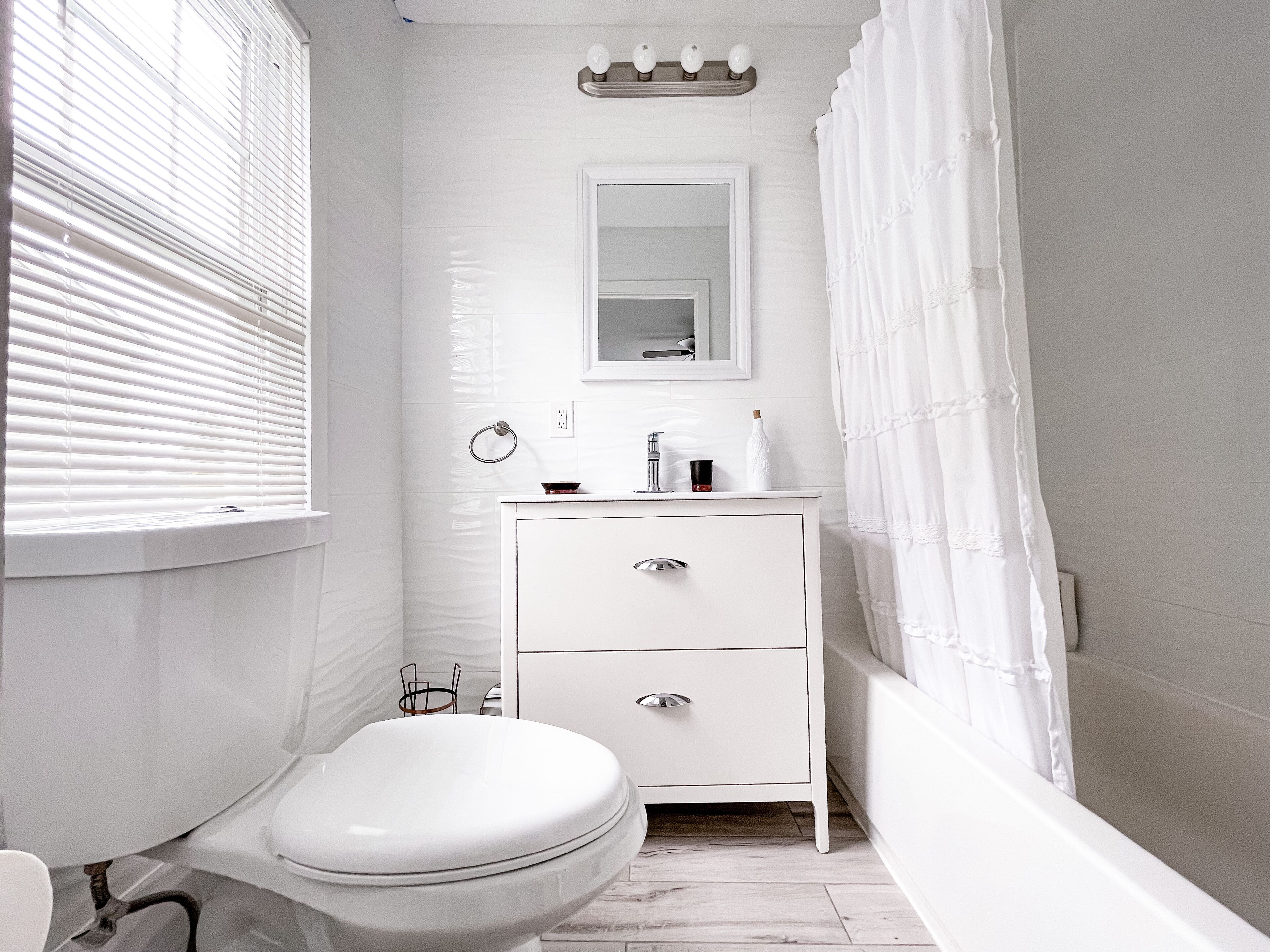 A small, white bathroom with a toilet, sink, and mirror.
