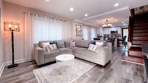 A modern living room with a sectional sofa, a round coffee table, and a floor lamp. - Cheerful & Modern Home w/ a Walkout Deck Area (Glenside)