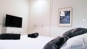A hotel room with a bed, a TV on a dresser, a wardrobe, and a framed picture on the wall. - Panorama Beach - Brisa del Mar Apartment (Torrox-Costa)