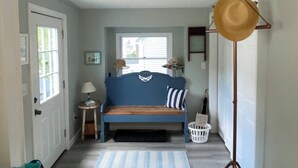 A bedroom with a blue bed, a striped rug, and a hat stand.