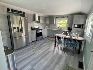 Una cucina moderna con elettrodomestici in acciaio inossidabile, mobili grigi e un'area pranzo con due sedie.