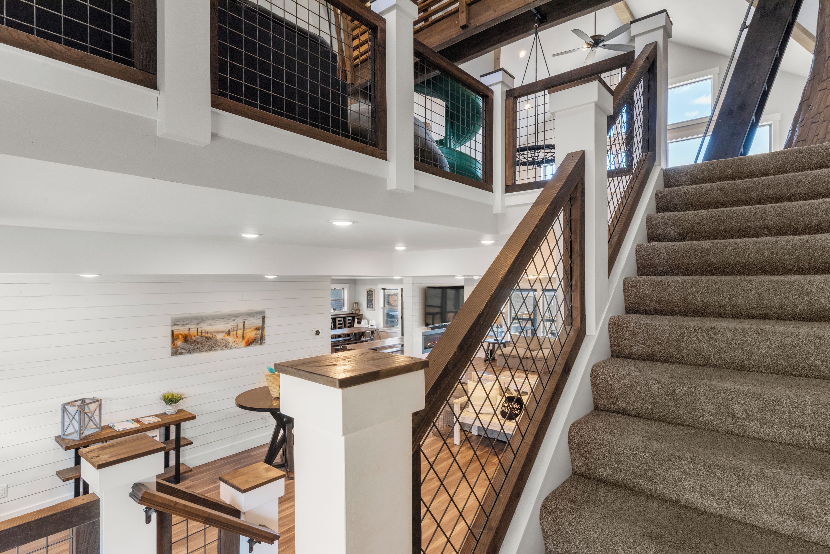 Un intérieur à plusieurs niveaux, avec un escalier, des rampes en bois et un espace cuisine.