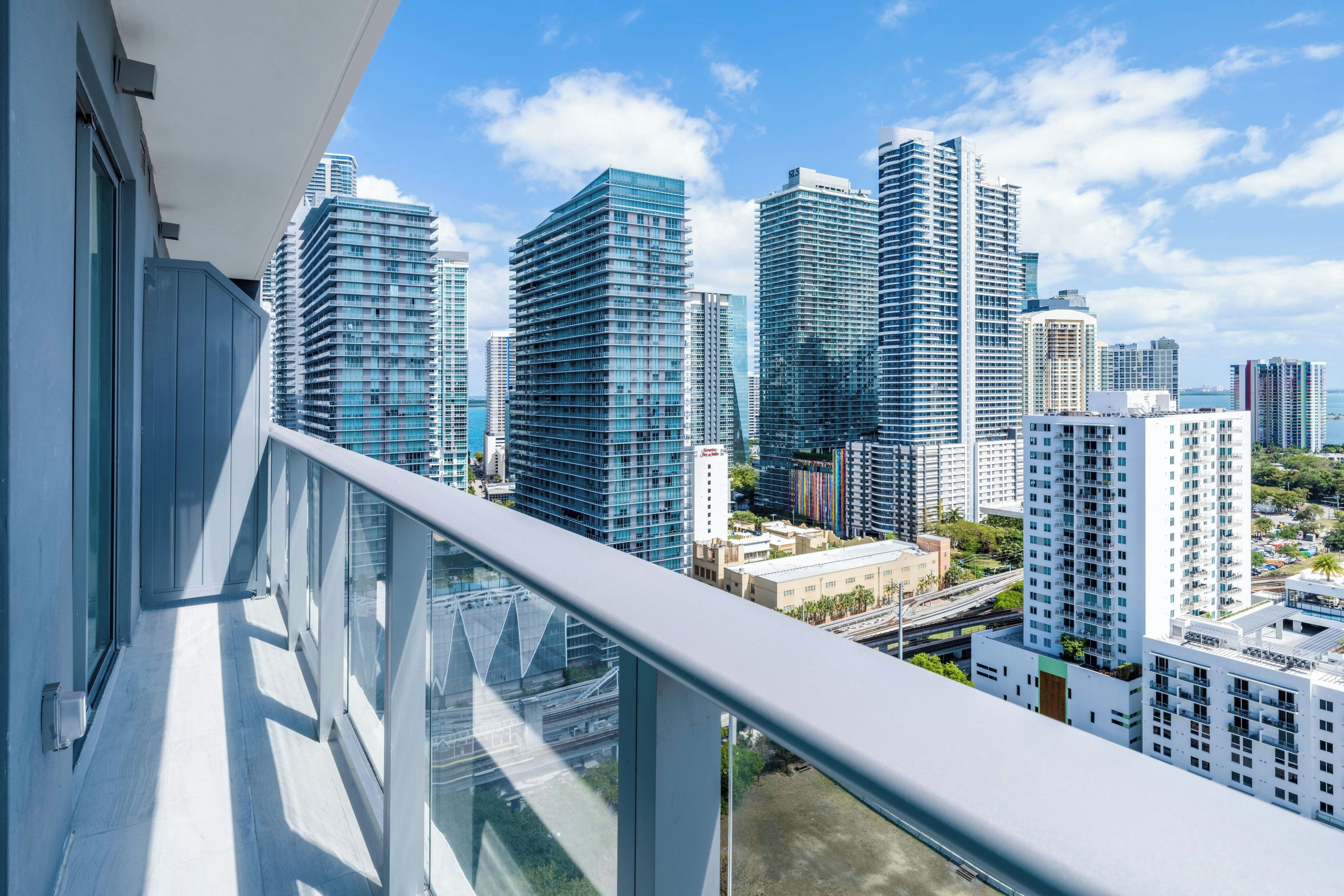 A high-rise building with a glass facade, surrounded by other tall buildings, and a clear sky.