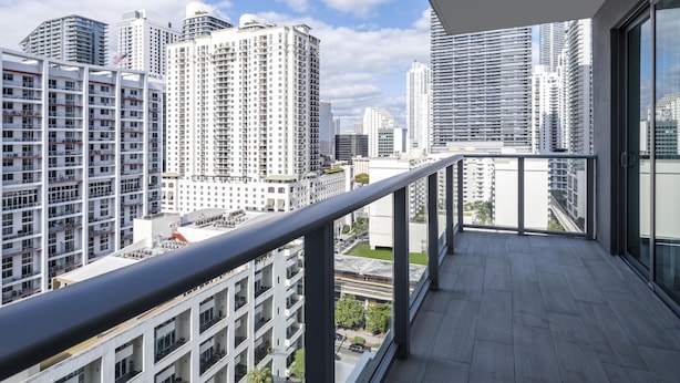 Un balcon offrant une vue sur la ville, avec de hauts immeubles et un ciel dégagé.