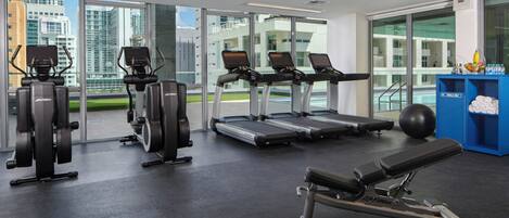 A gym with cardio machines, a bench, and a blue water station.