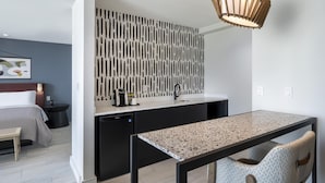 Une chambre d’hôtel moderne dotée d ’une kitchenette, d’un coin repas et d’un lit.