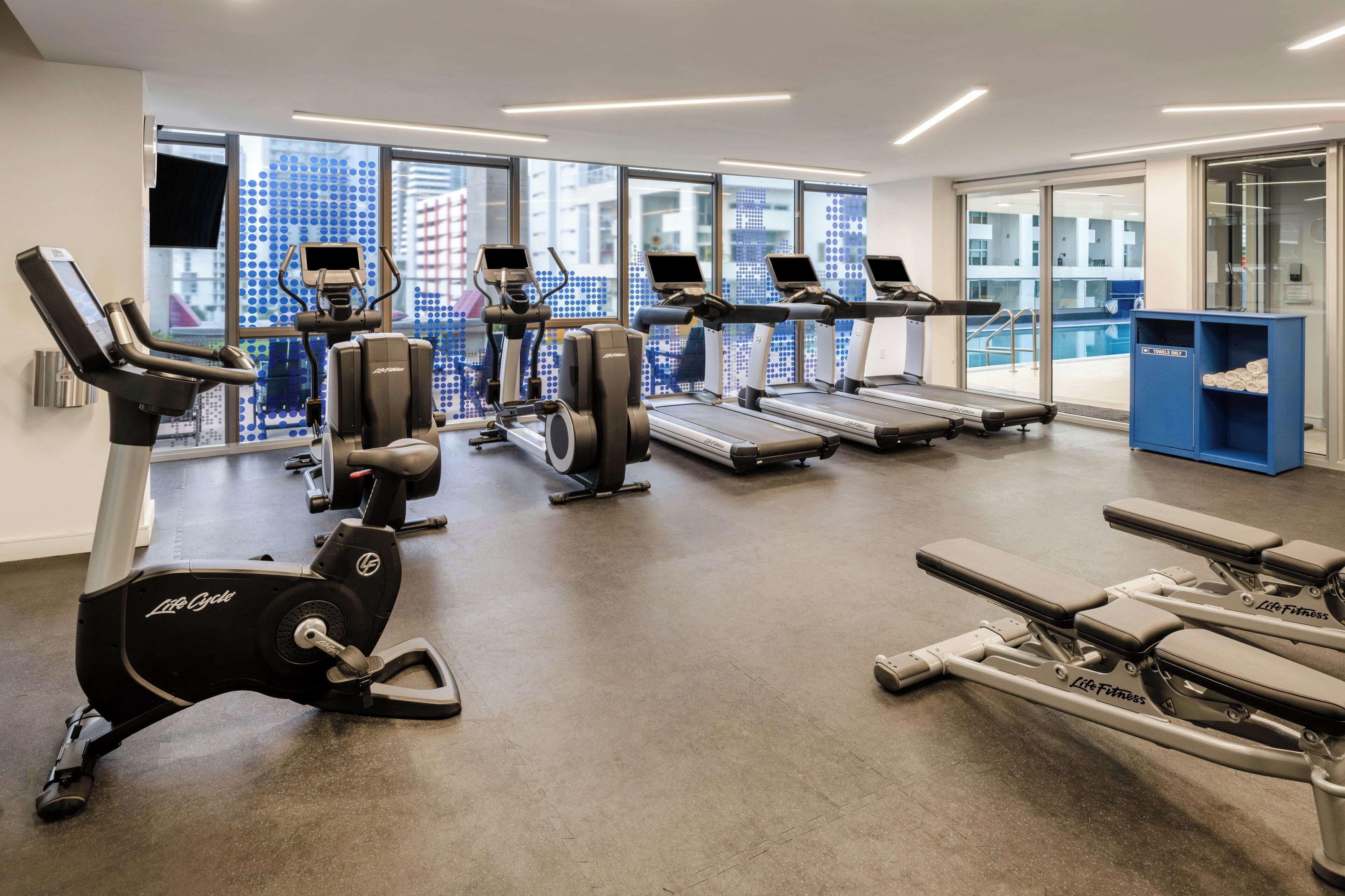 Un centre de remise en forme équipé de machines de cardio, de machines de musculation et d’une zone dédiée aux exercices de développé couché.