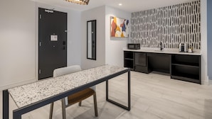 Une chambre d’hôtel moderne dotée d’une table à manger, d’un coin cuisine et d’un panneau décoratif mural.