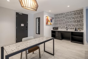 A modern hotel room with a dining table, a kitchen area, and a decorative wall panel. - Atwell Suites Miami Brickell by IHG (Miami)