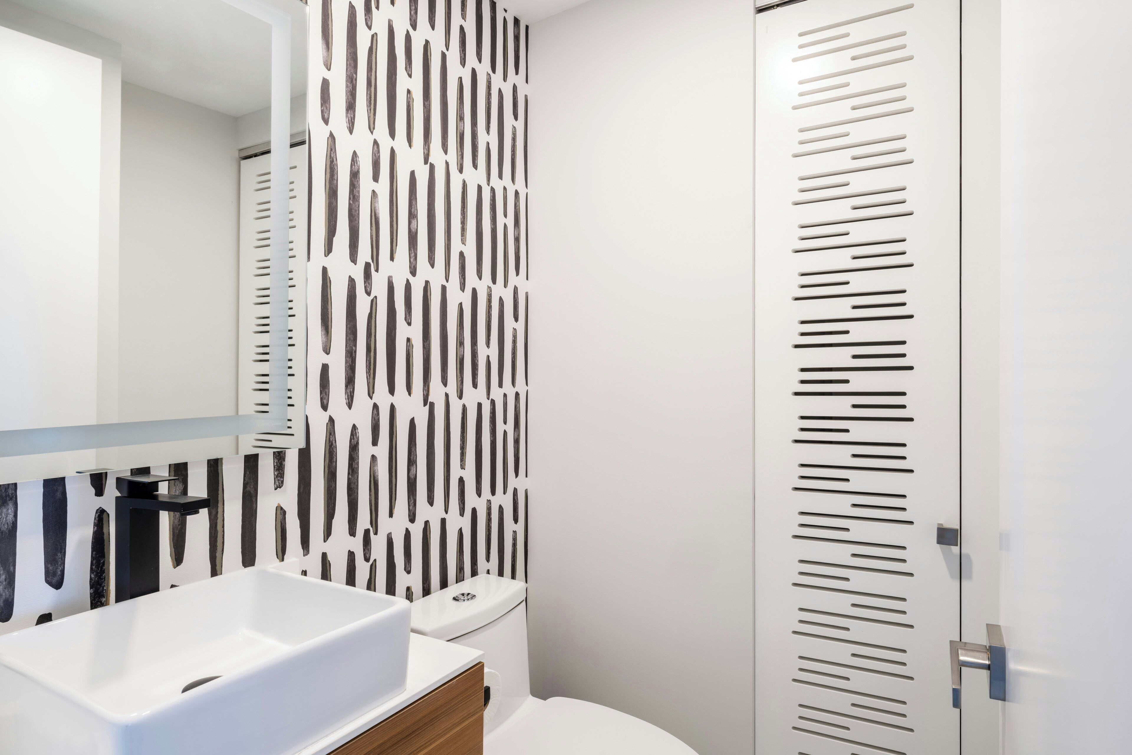 Une salle de bain moderne avec un lavabo blanc, un miroir et des toilettes.
