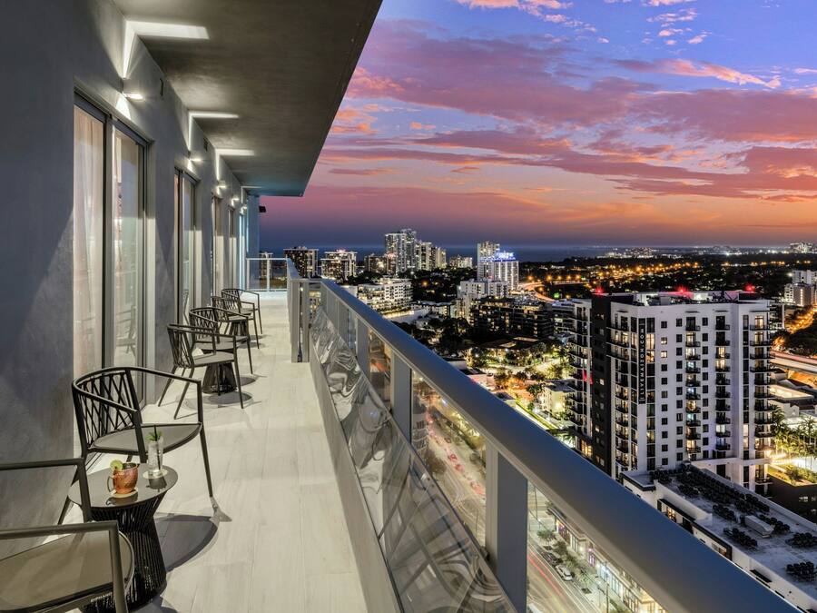 Un balcone con posti a sedere all'aperto, affacciato su una città al tramonto.