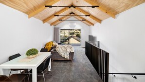 A modern interior with a high ceiling, a dining area with a table and chairs, a sofa, and a view through a large window. - 3 Bedroom Modern Alpine Apartment (Queenstown)