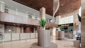 A modern lobby with a reception desk, a 'Goddvitel' sign, a 'Baby Lounge', and a large central planter. - GoldVitel Hotel Surabaya (Surabaya)